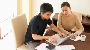 guy using a laptop with a lady looking in